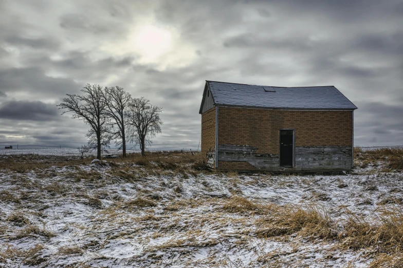 an old brick building stands in a snow covered field
