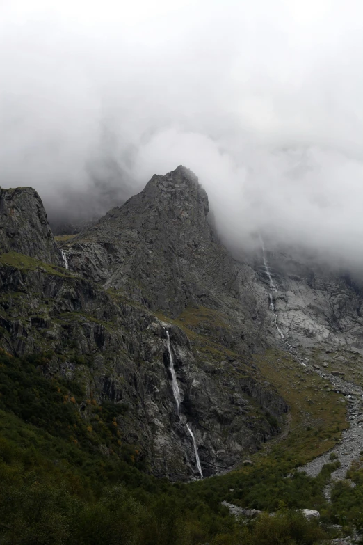 fog hanging off the sides of mountains on a cloudy day