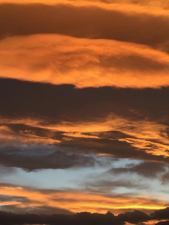 a plane flying through the cloudy sky during sunset