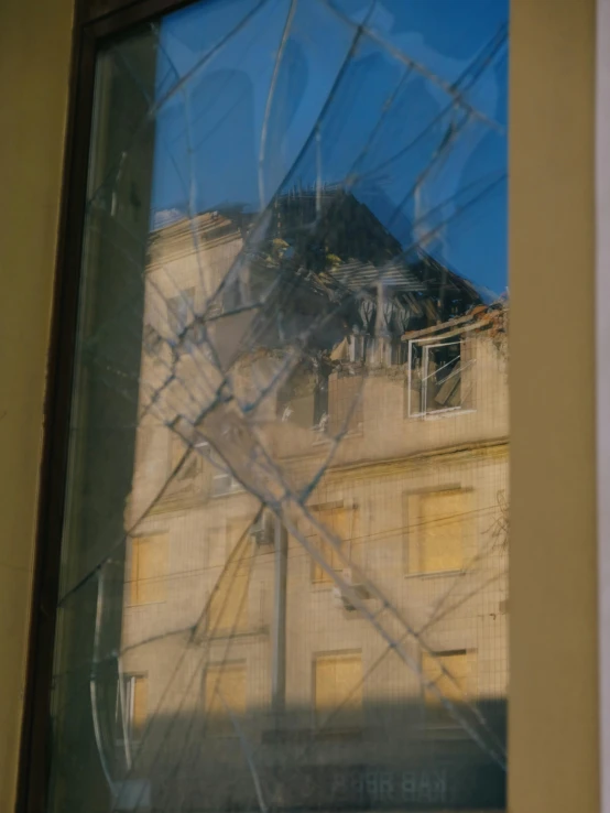 a house behind a window with broken glass