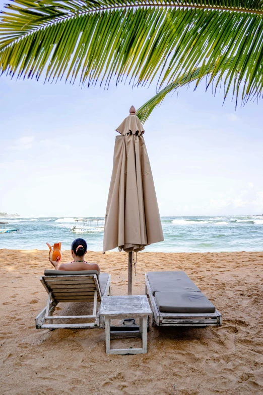 a man sitting in a lawn chair under an umbrella on a beach