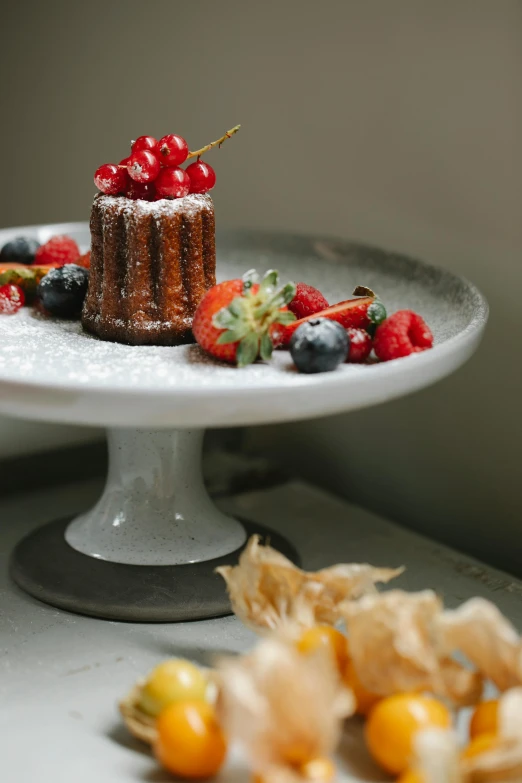 a chocolate cake covered in berries sitting on top of a white cake platter