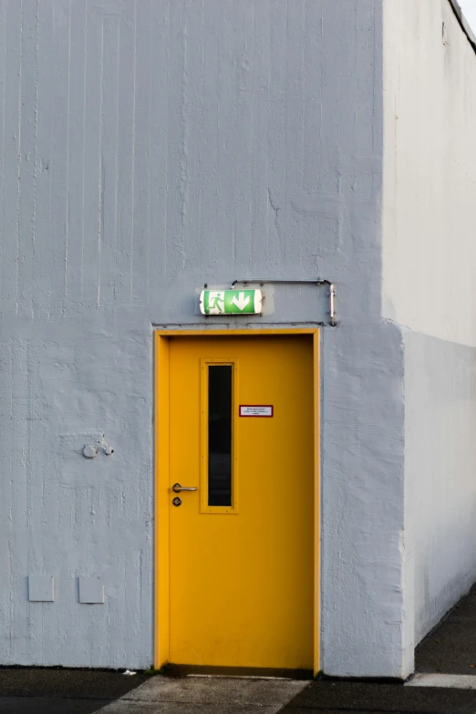 yellow door against a gray wall next to street