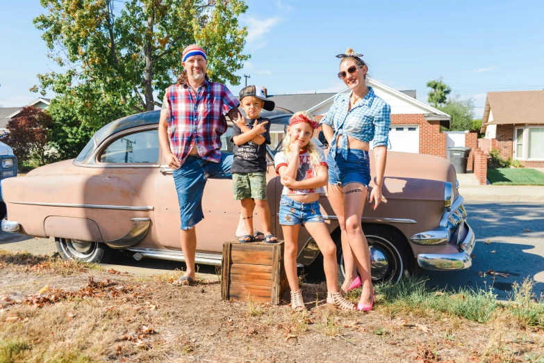 a man and three children posing next to an old truck