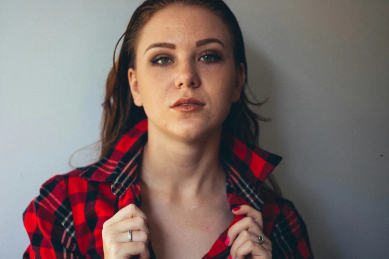 an attractive young woman poses with her checkered shirt on