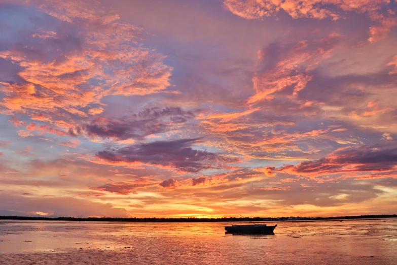 a small boat on the ocean at sunset