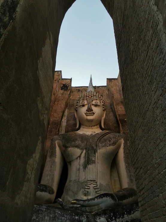 a stone statue stands in an arched passage