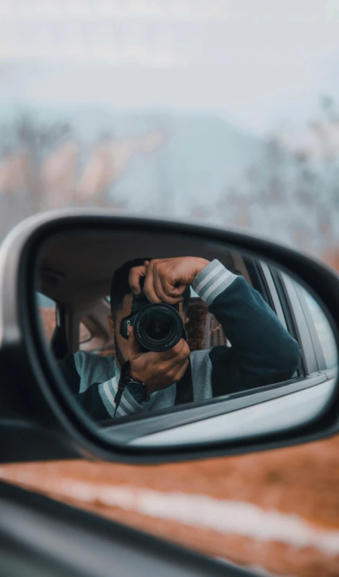 a man is taking a picture through a rear view mirror