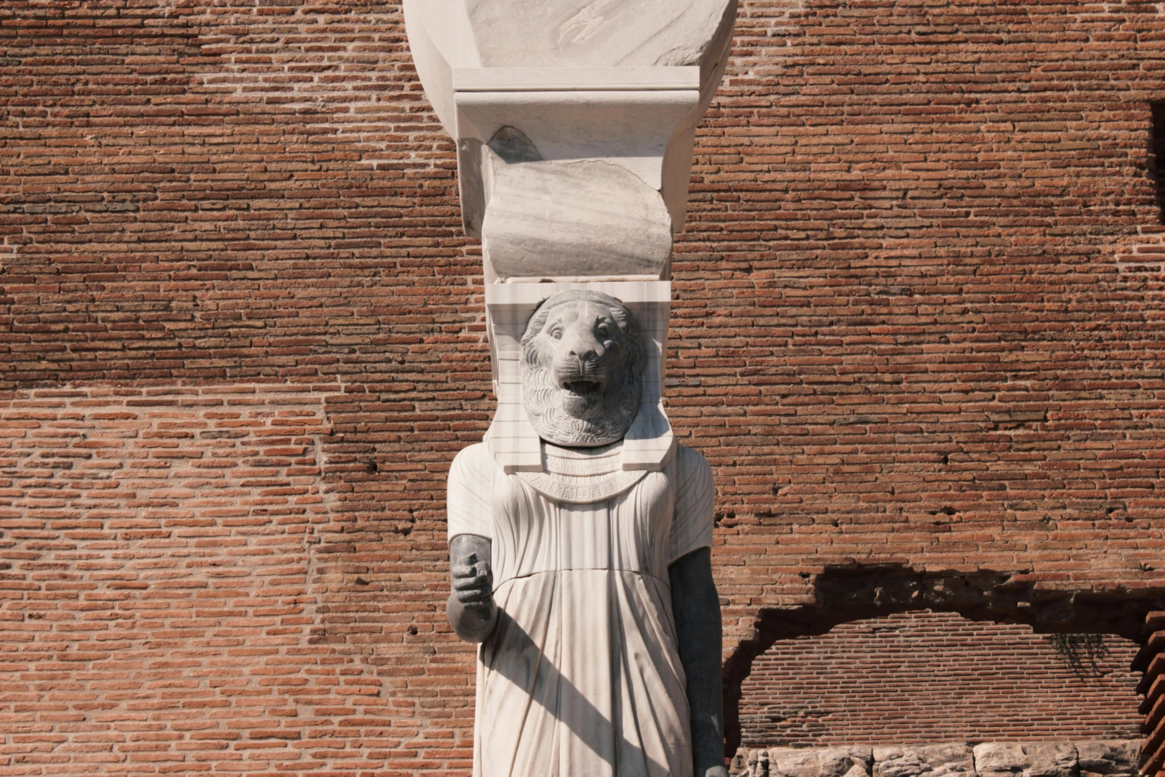 a large white statue is near the brick wall