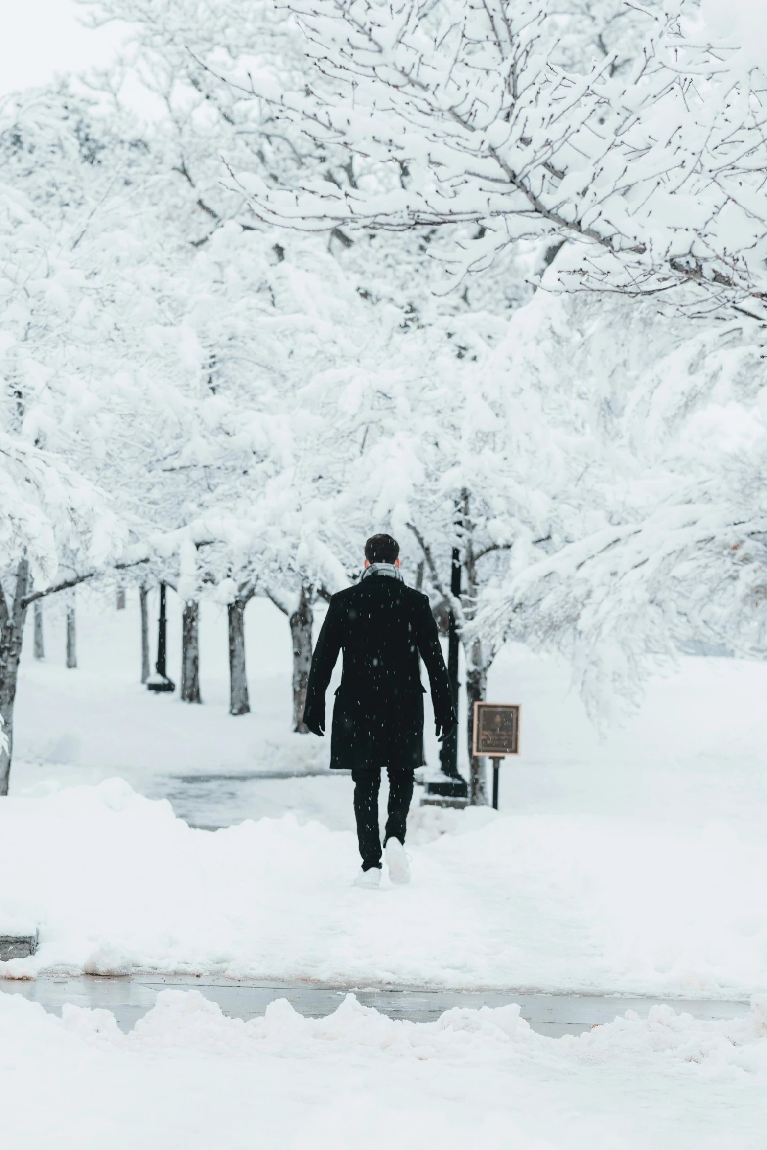 a man walking in deep snow near park benches