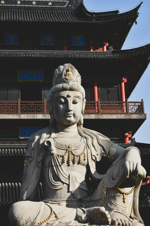 a large statue sitting in front of a tall building