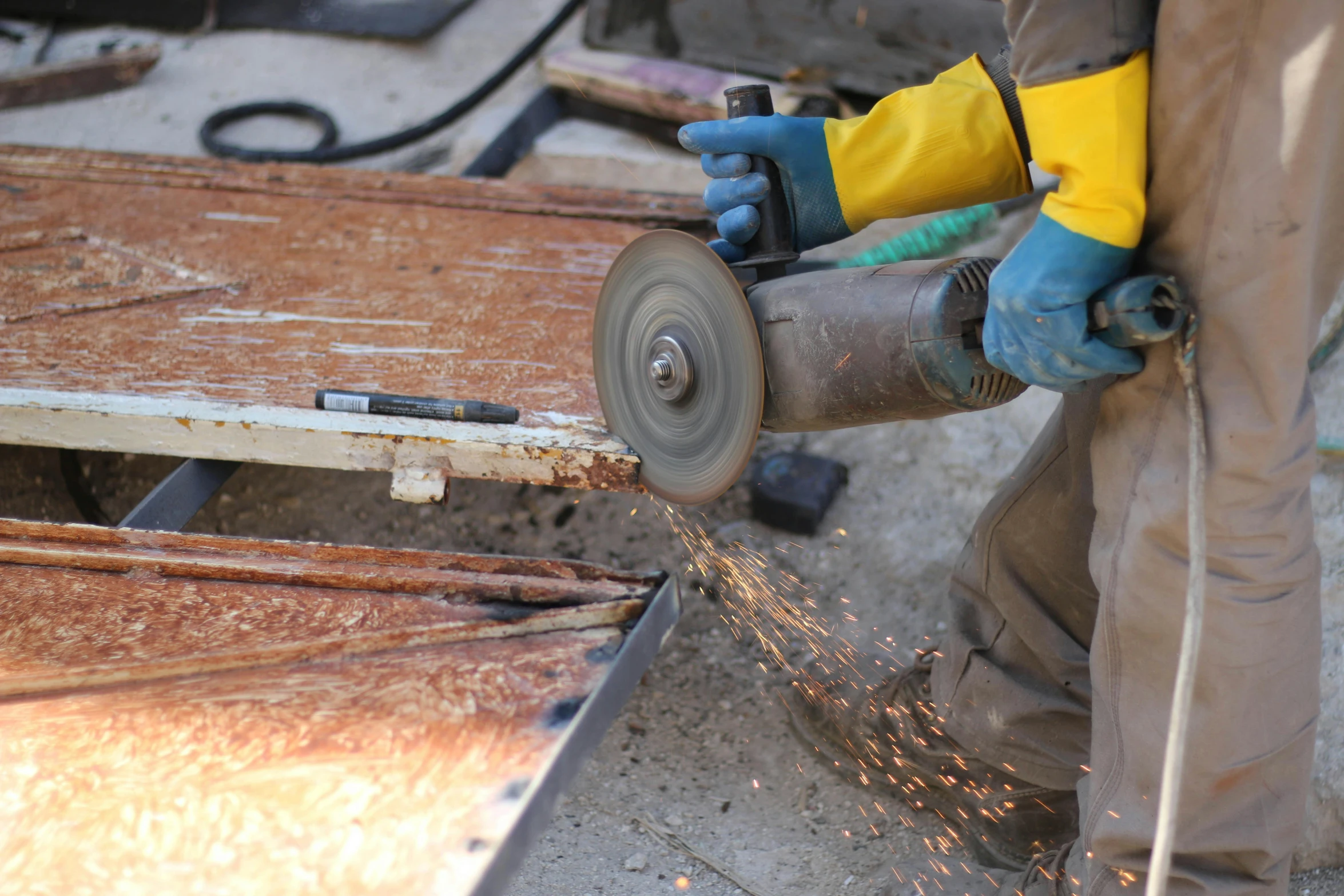 welder grinding metal with grinder on table