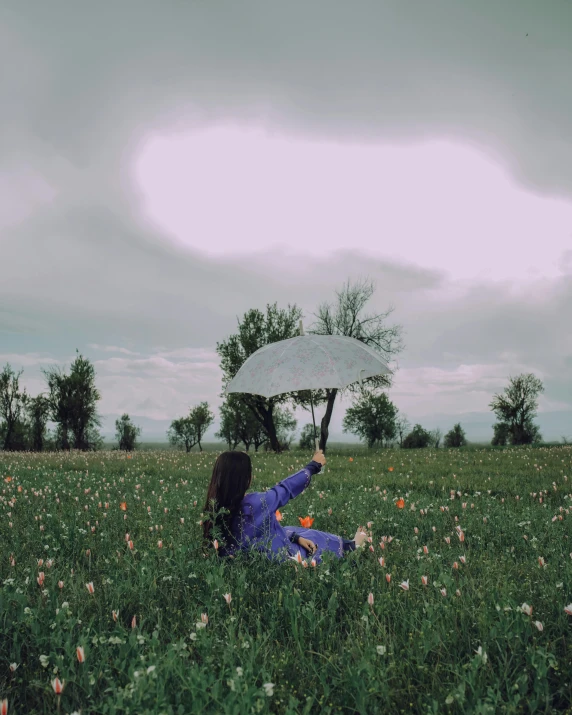 a girl sitting in a field with a umbrella