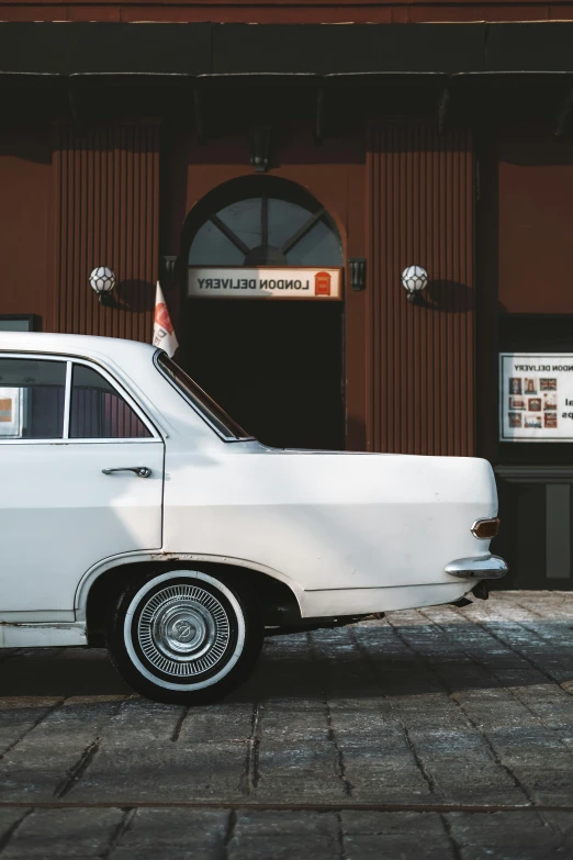 the old car is parked in front of the brick building