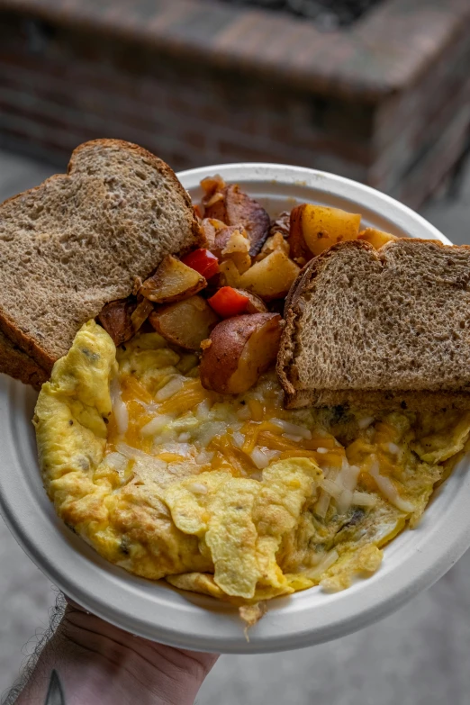 a person holding a bowl with eggs and toast in it