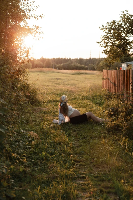 a person laying on the ground in a field with a fence