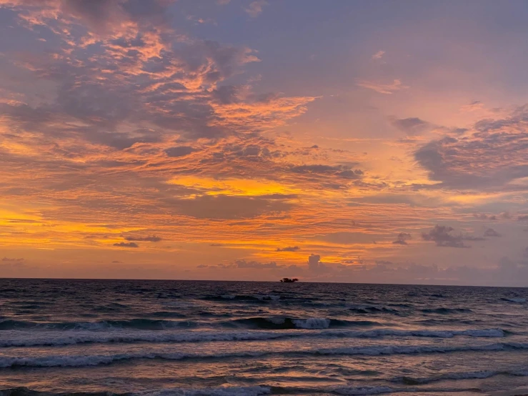 the waves of an ocean are moving near the shore as the sun sets