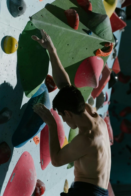 man climbing up a wall of colorful rock climbing