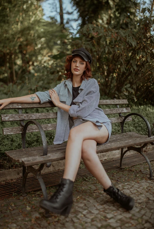 a woman in short shorts and a hat sits on a bench