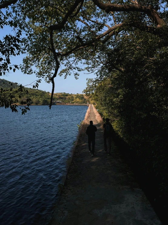 two people walking along a path next to the water