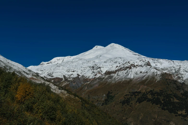 a large white mountain sitting on top of a lush green hillside