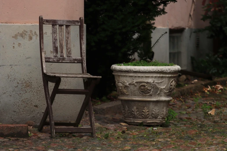 a old wooden chair and flower pot next to each other