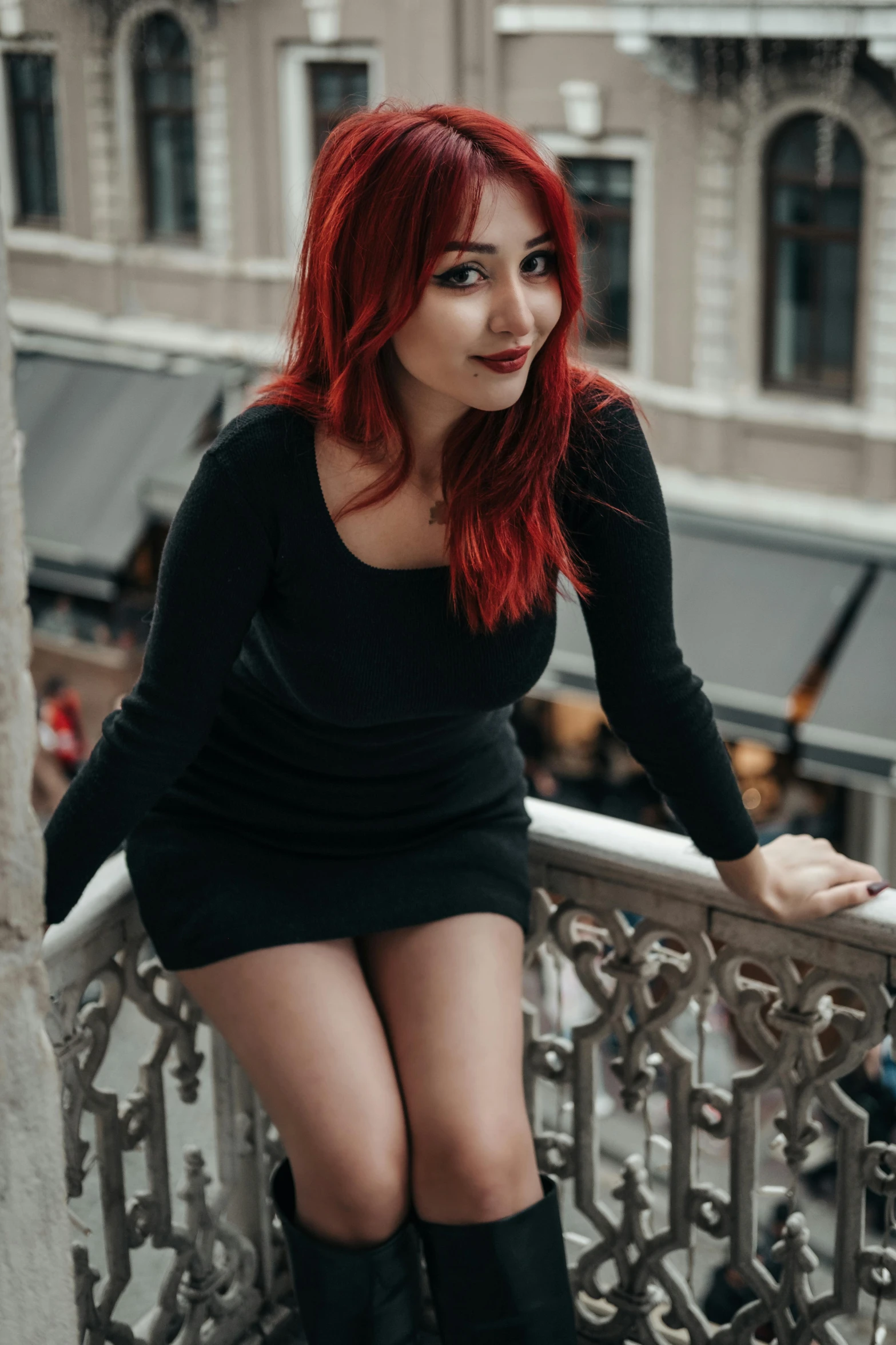 young redhead girl in long dress sitting on the balcony