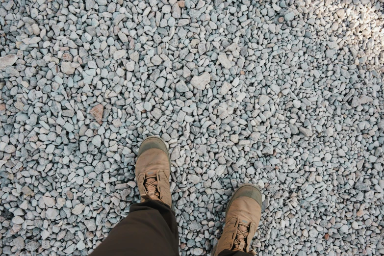 someone wearing khaki and tan shoes, standing on a rocky area