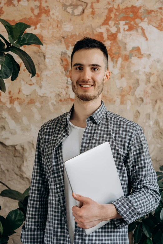 a man is smiling while holding a laptop computer