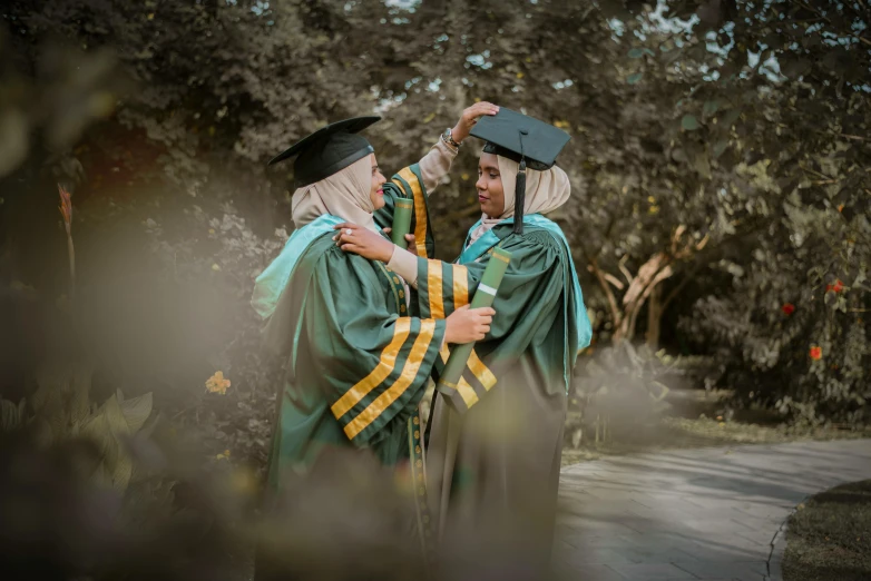 two women in graduation gowns hug each other