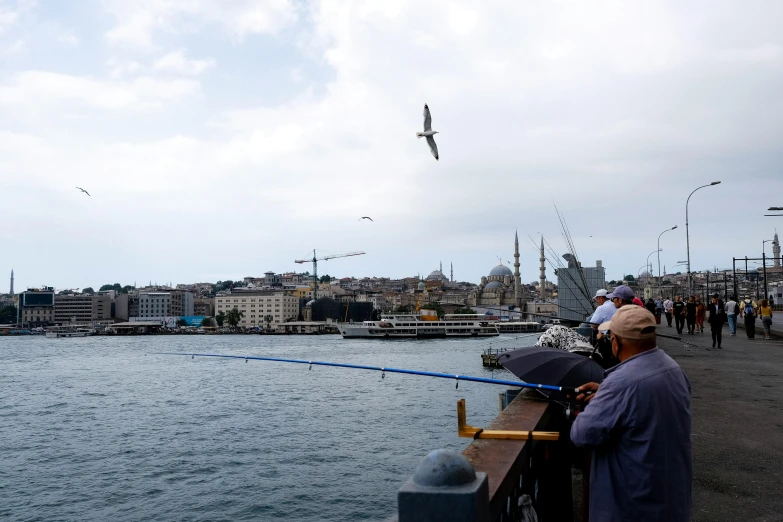 people near the sea fishing while several other ships float in the water