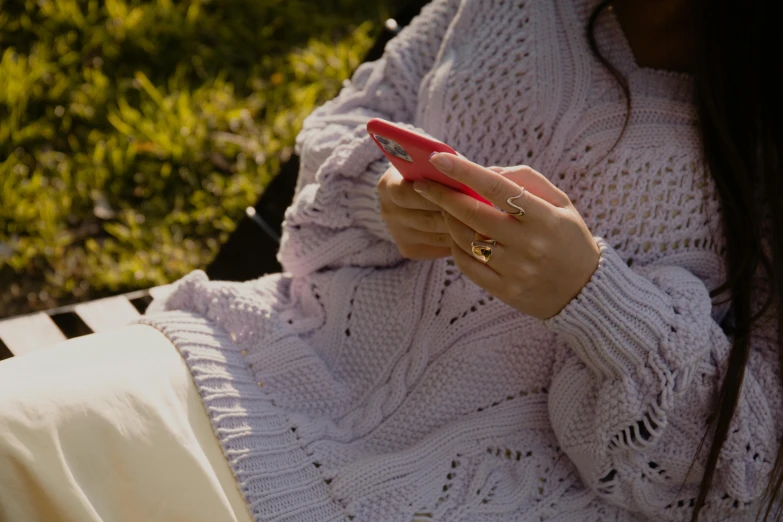 a woman wearing a white sweater is looking at her cellphone