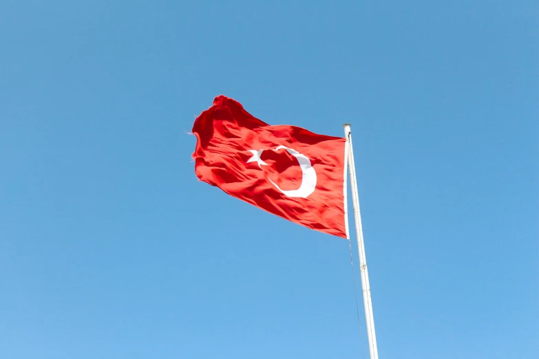 the turkish flag flying in front of a blue sky