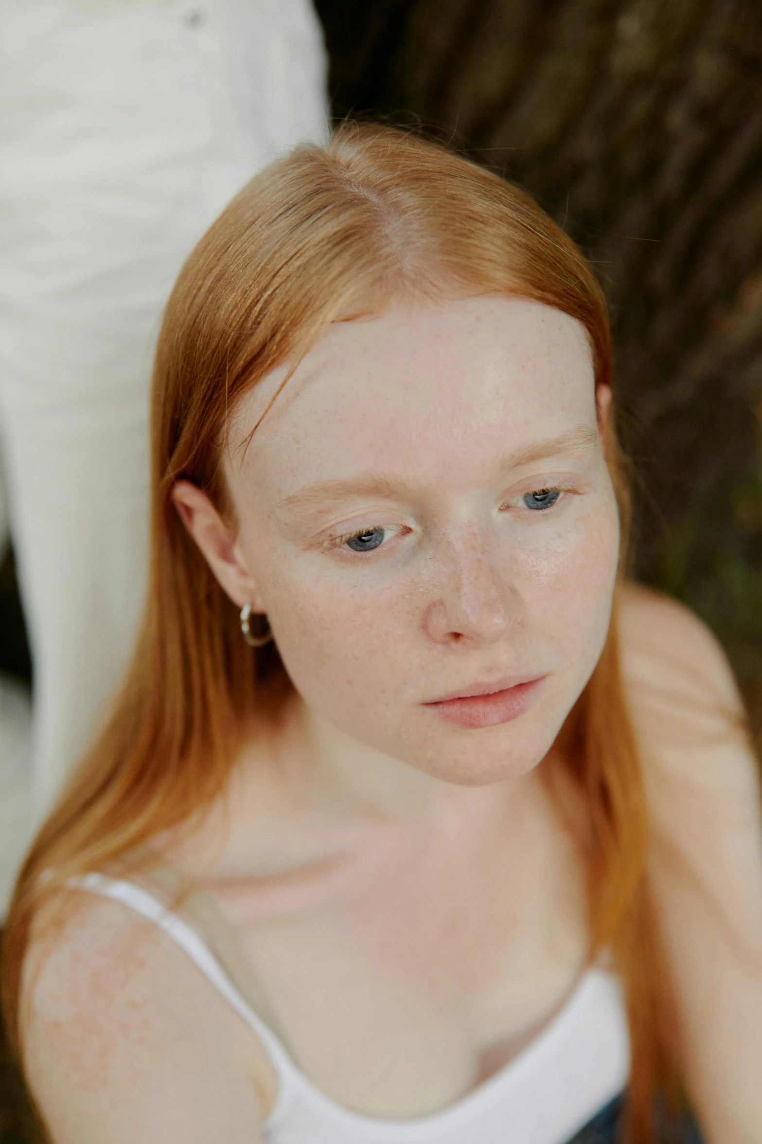 a woman with red hair and white tank top posing for a picture