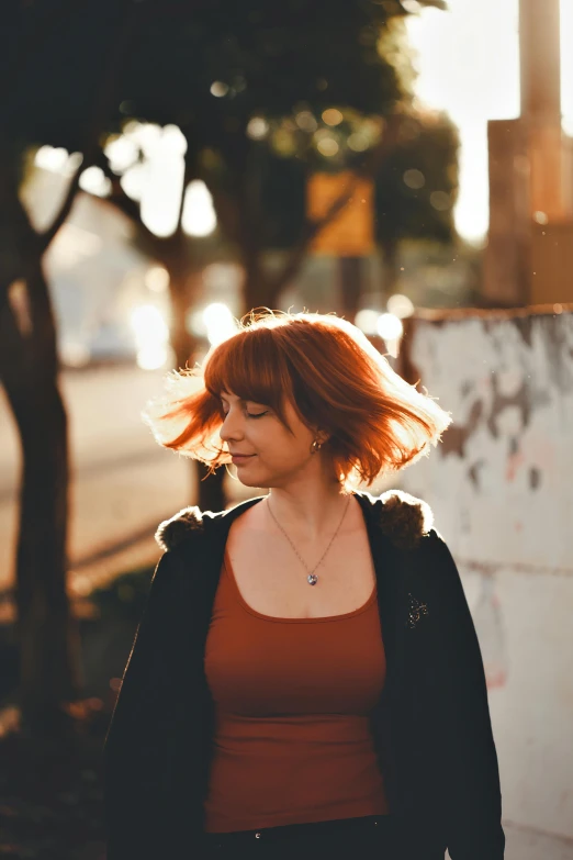 a woman standing on a sidewalk with long red hair