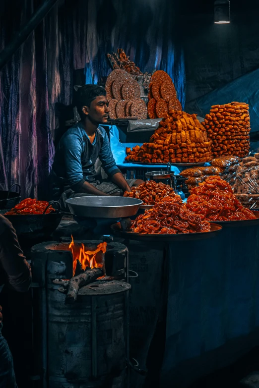 the man sits at his stand selling food