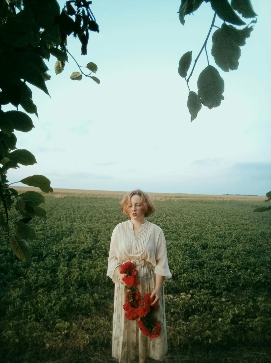 a woman in an old - fashioned white dress standing under a tree in a field