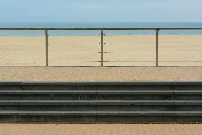 a beach with stairs near by and a bench