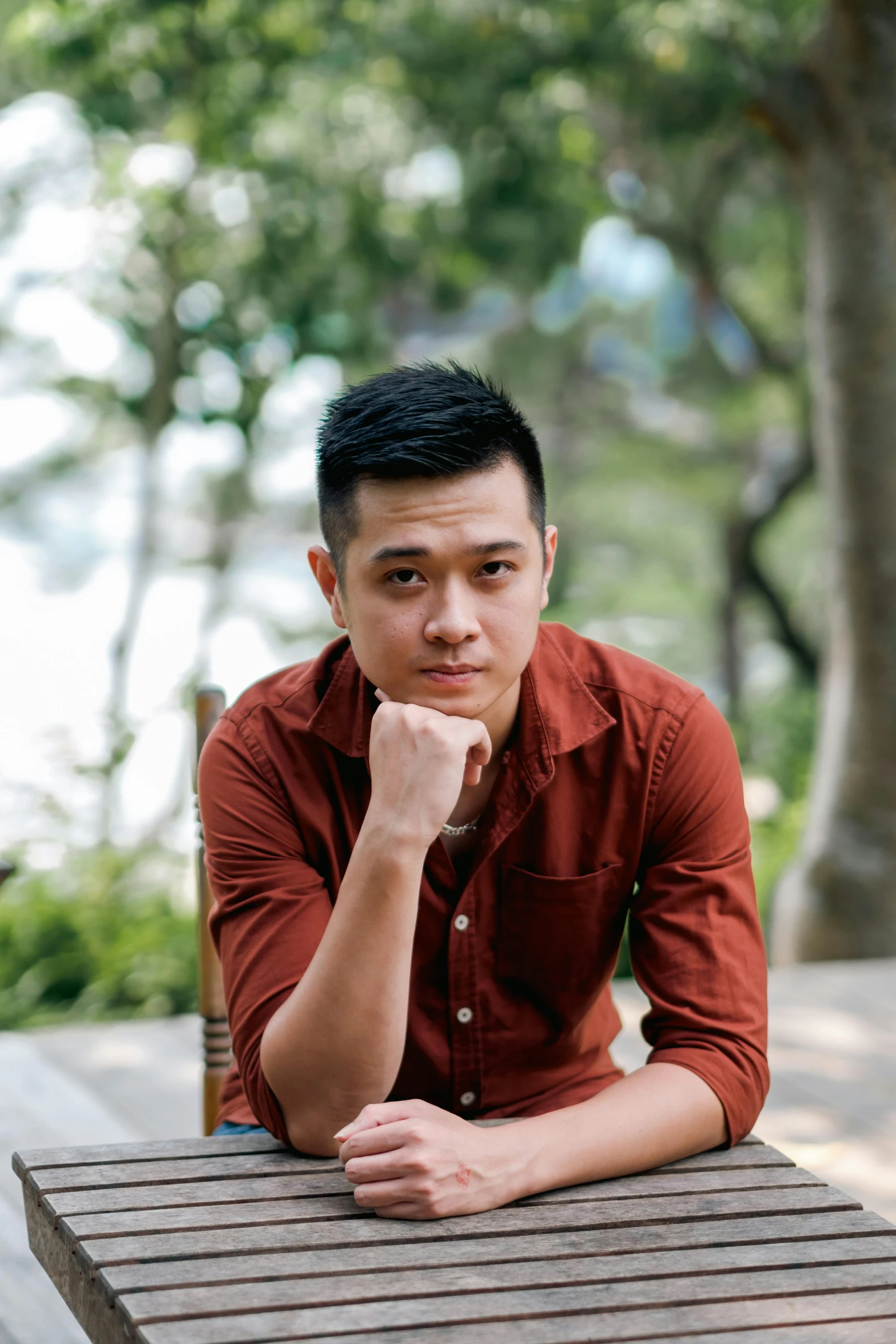 a young man wearing a red shirt poses for a portrait