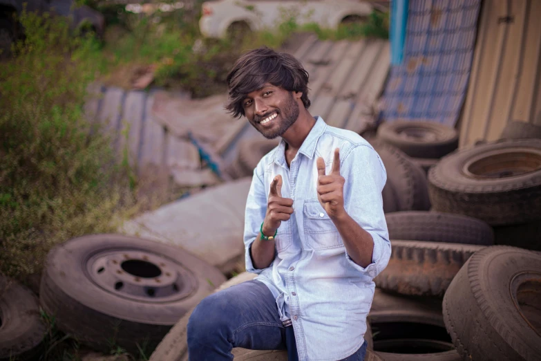 a man gives a thumbs up in front of junk piles