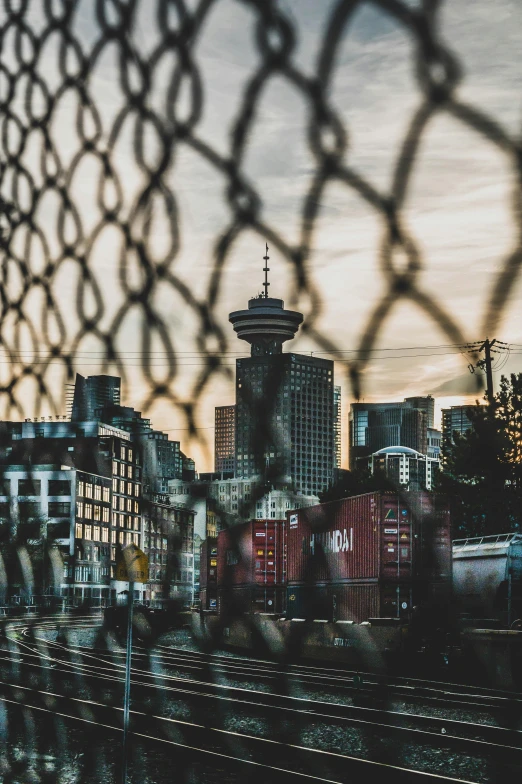 view of city through fence with train track passing in foreground