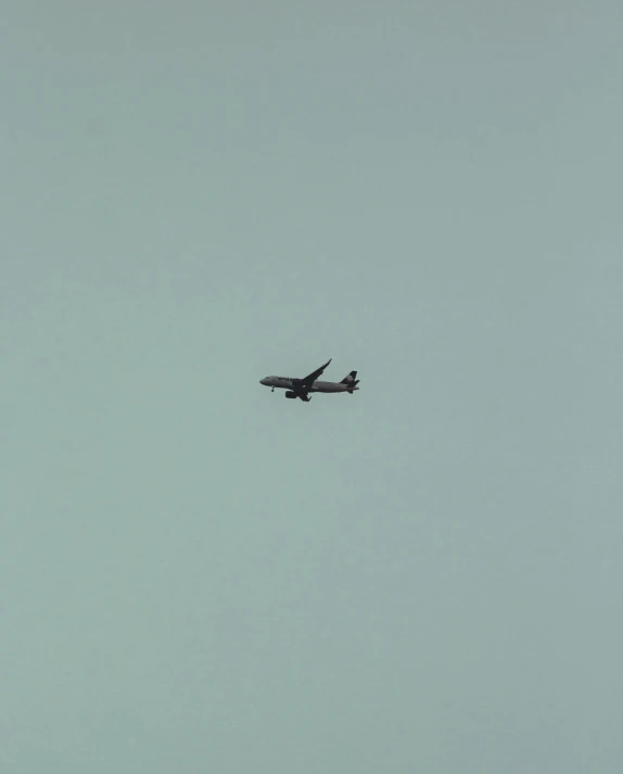 an airplane is flying on a light blue sky