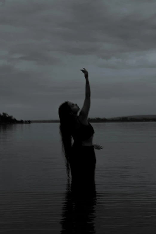 a woman is standing in water with her arm up