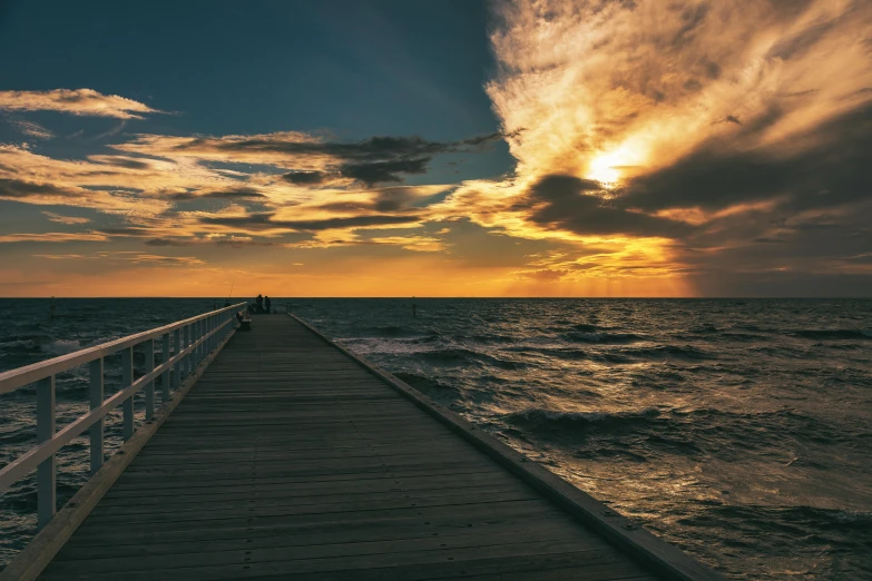 the sun rising over the ocean with clouds in the sky