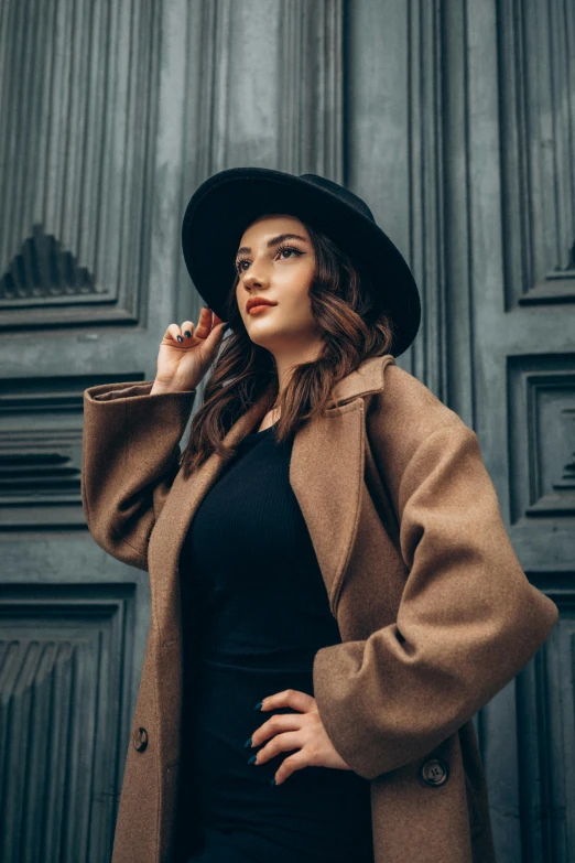 a woman in a hat, dress and coat is talking on her phone