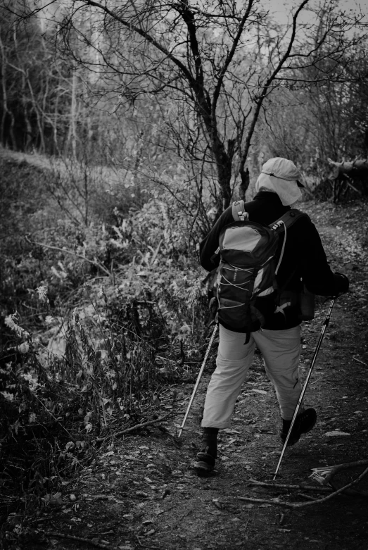 a backpacker in black and white looks down a trail