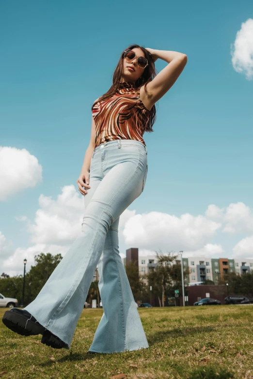 a woman wearing high waist jeans poses in a grassy field