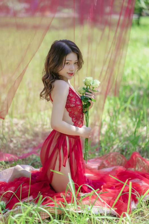 a little girl sitting in a field wearing a red dress