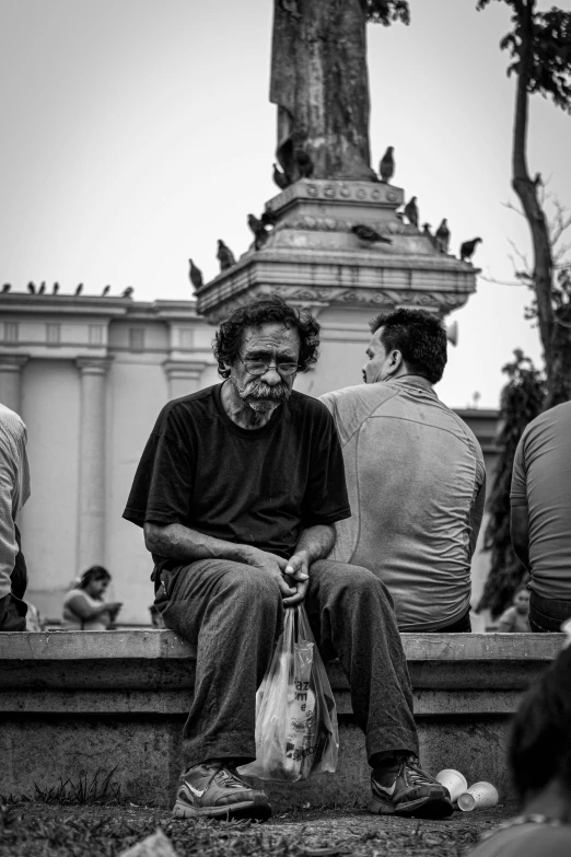 there are three men sitting near a statue