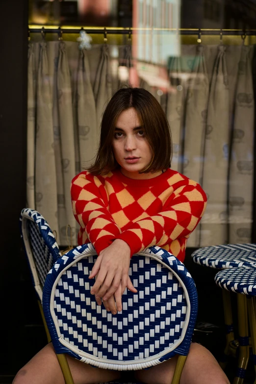 a woman sits alone wearing an unusual sweater